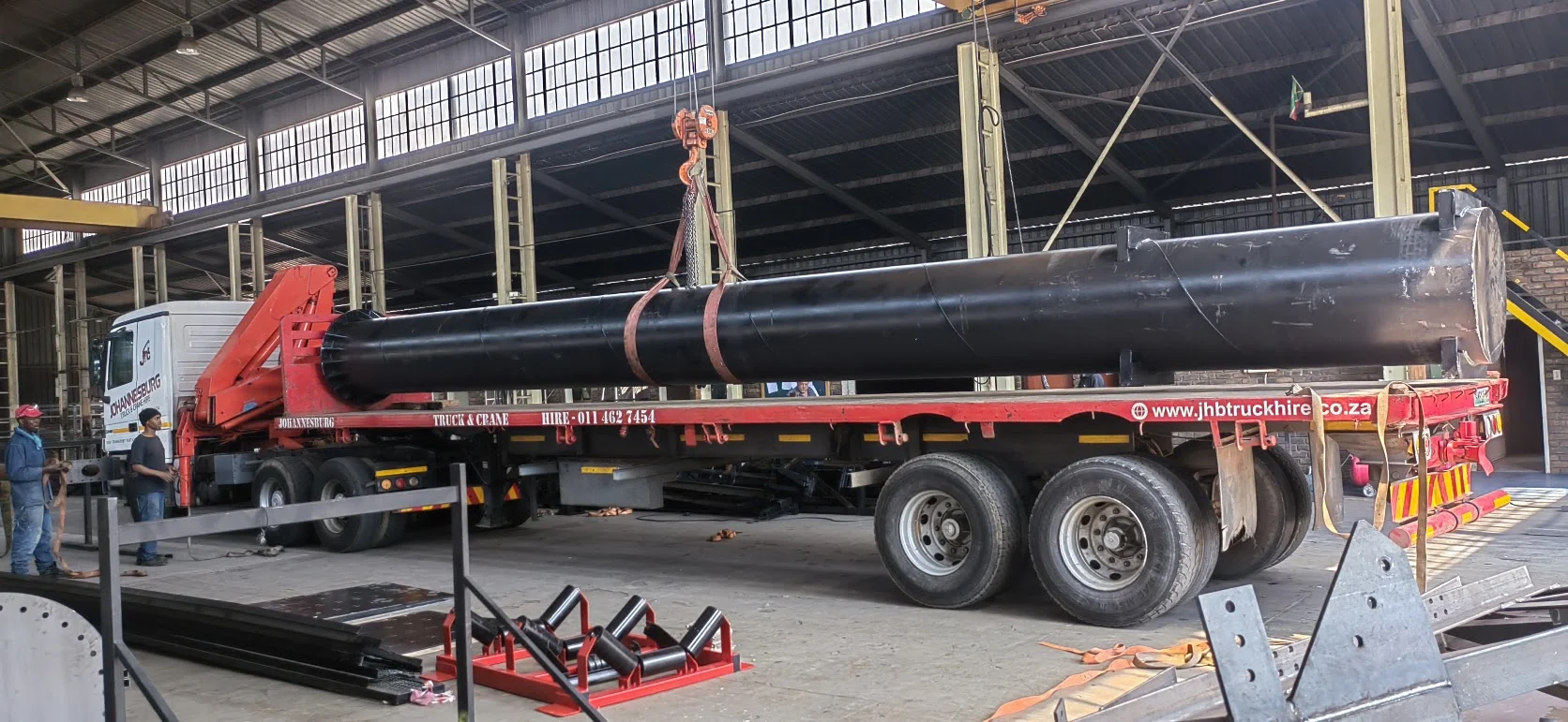 Branded JHB flatbed trailer being loaded with a large steel component