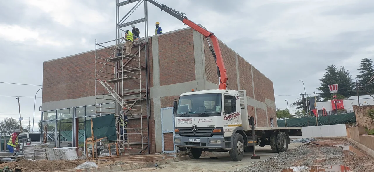 JHB crane truck lifting a steel structure at a construction site