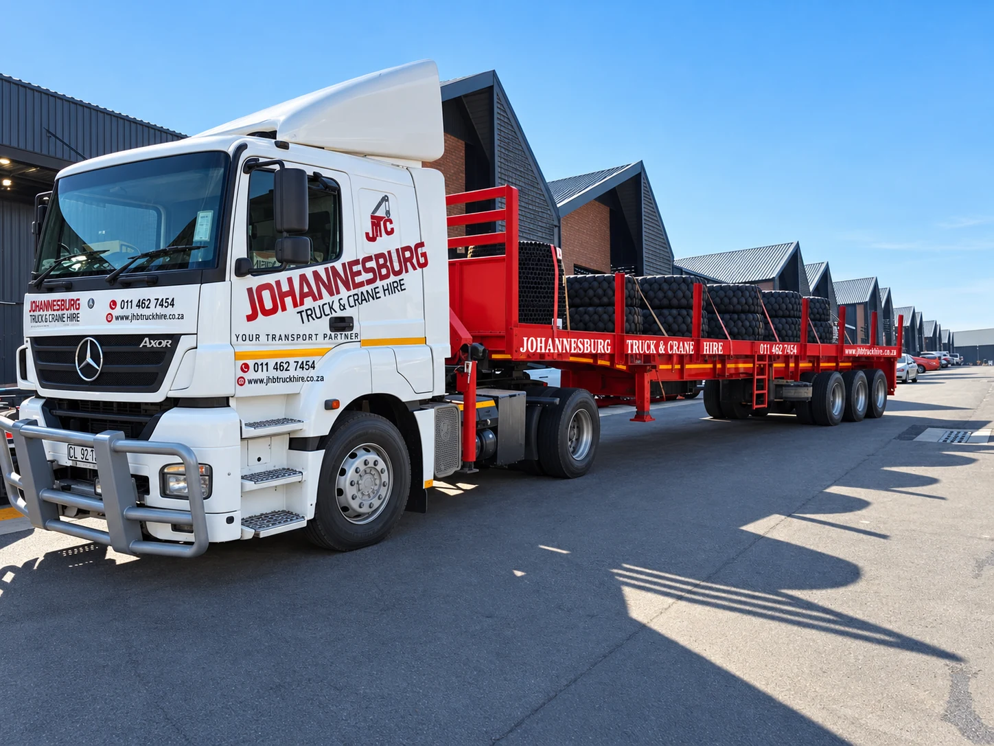 Enhanced JTC crane truck transporting a long industrial load